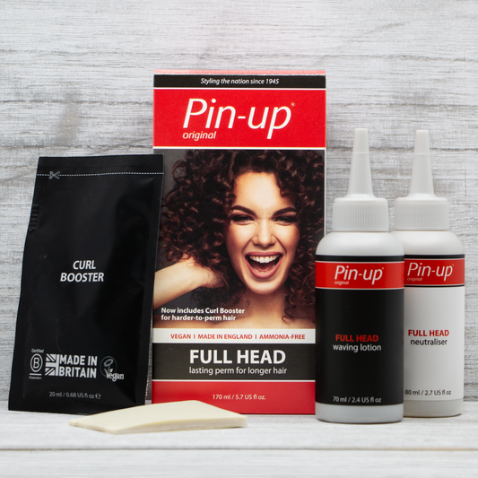 The Full Head Perm by Pin-up Perm displayed on a surface. The kit includes a box with a smiling woman on the front and the text "Pin-up original FULL HEAD," two white bottles labeled "FULL HEAD waving lotion" and "neutralizer," a "Curl Booster" packet, and a small foam applicator—everything you need for long-lasting curls.